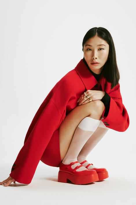 Model in a red skirt suit with knee high white socks wearing a pair of red Farah platform mary janes
