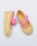Side and top view of a pair of yellow Hip Ballerina baby flats with flower on strap and pink trim