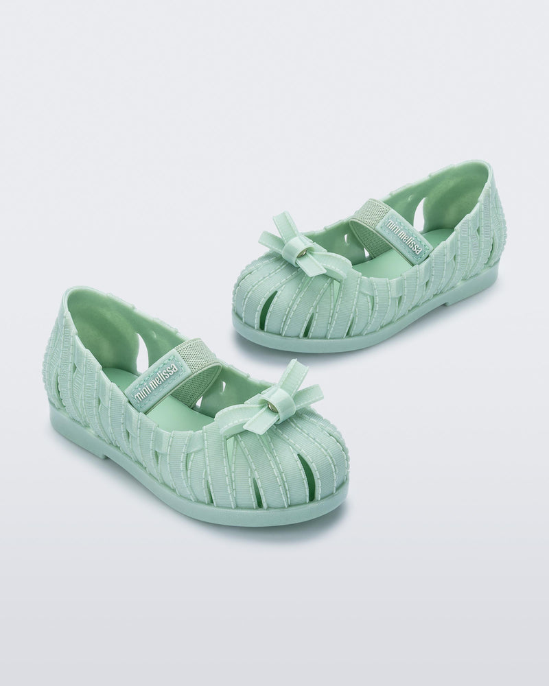 Angled view of a pair of glitter green M Lover Ballerina baby flat with bow and strap