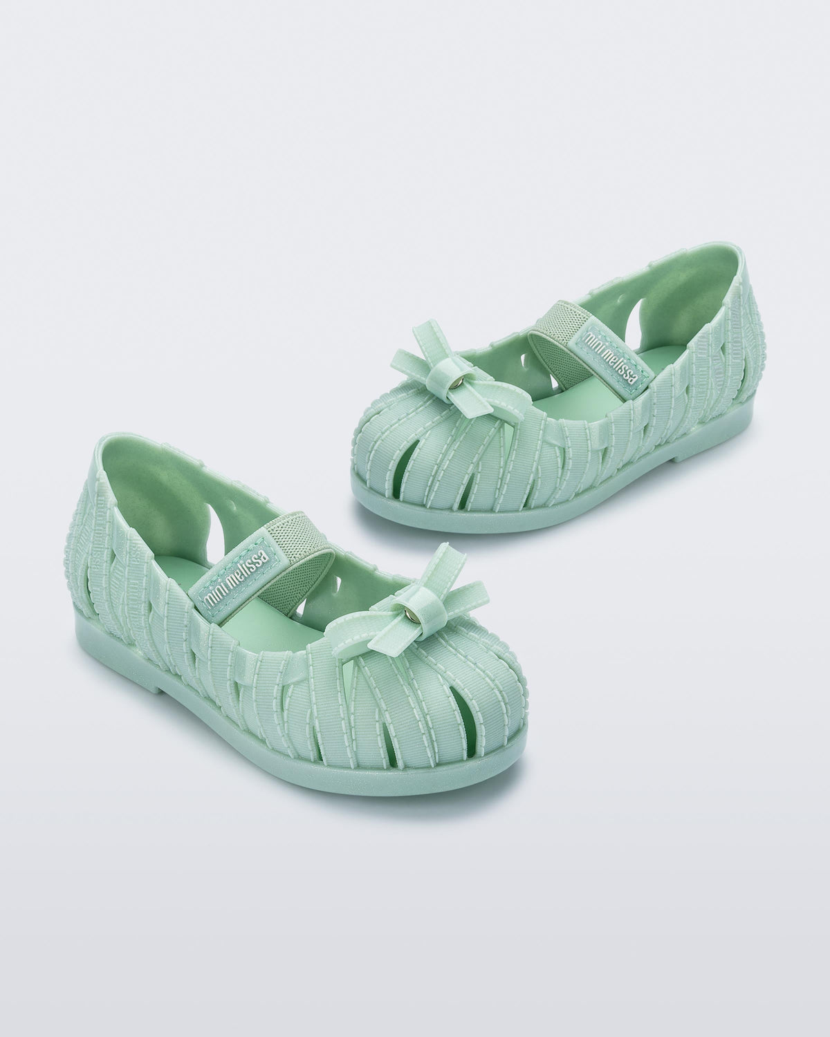 Angled view of a pair of glitter green M Lover Ballerina baby flat with bow and strap