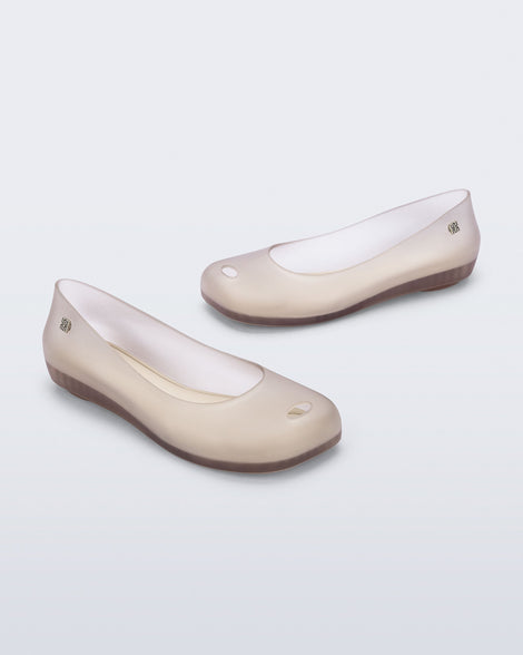 Angled view of a pair of clear beige Ultragirl Futura ballerina flats