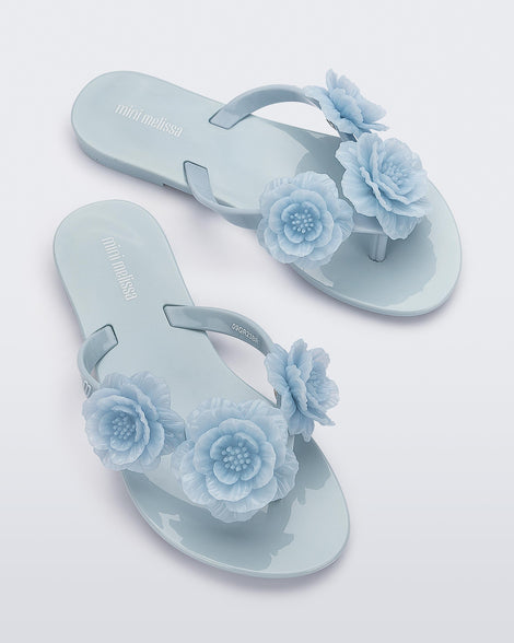 Top view of a pair of a blue Harmonic Springtime kids flip flop with three blue flowers.