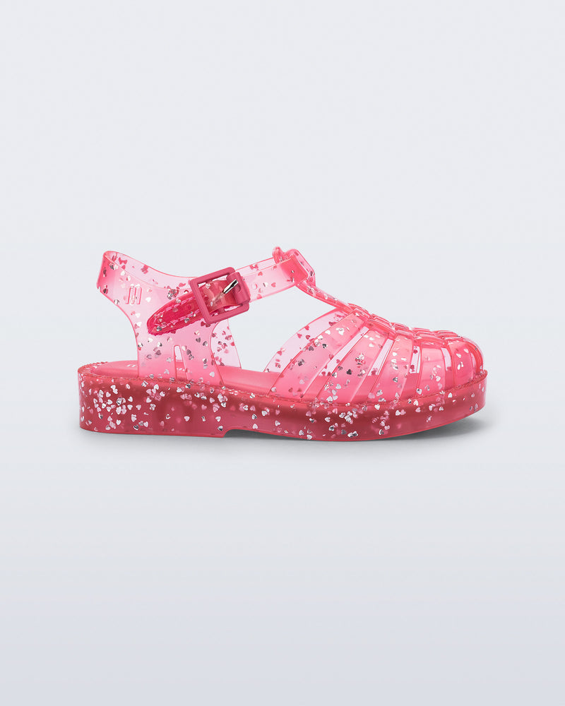 Side view of a pink Possession Elements baby sandal with glitter hearts
