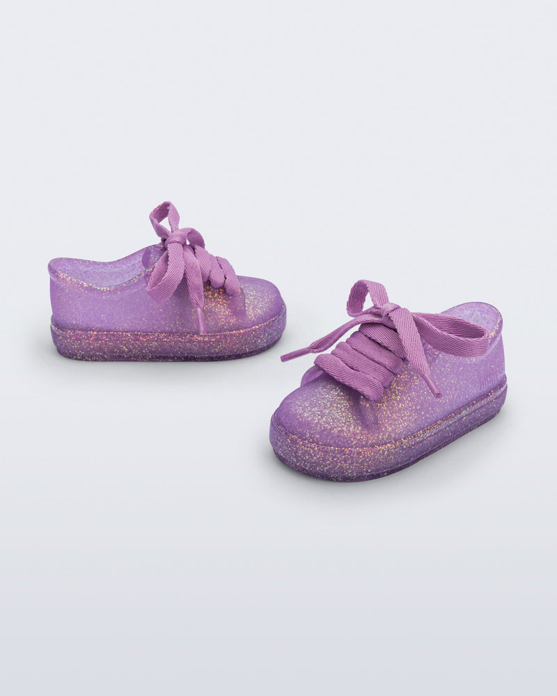 Side and angled view of a pair of glitter lilac baby Hip Sneakers with lilac laces