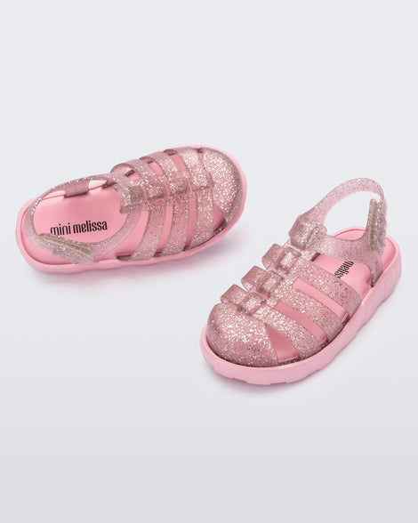 Angled view of a pair of glitter pink Megan baby sandals.