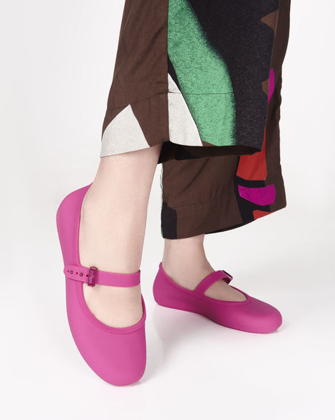 Model's legs wearing a pair of pink Soft adult flats with strap and pink buckle