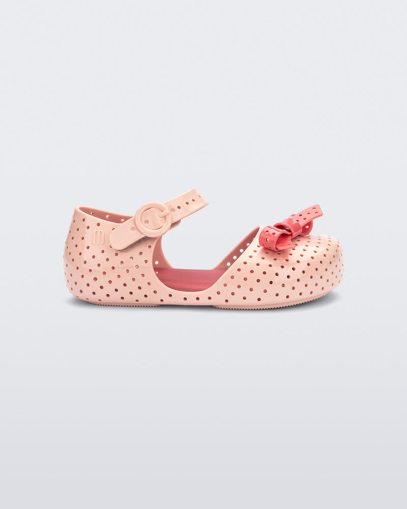 Side view of a light pink Pop baby flat with a red bow