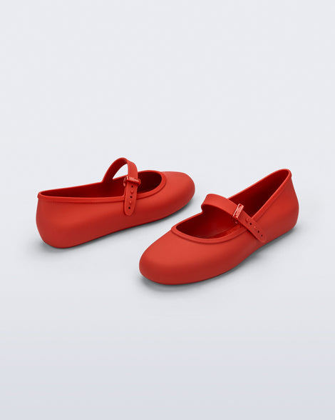 Side and front angled view of a pair of red Soft Ballerina flats with top buckle strap