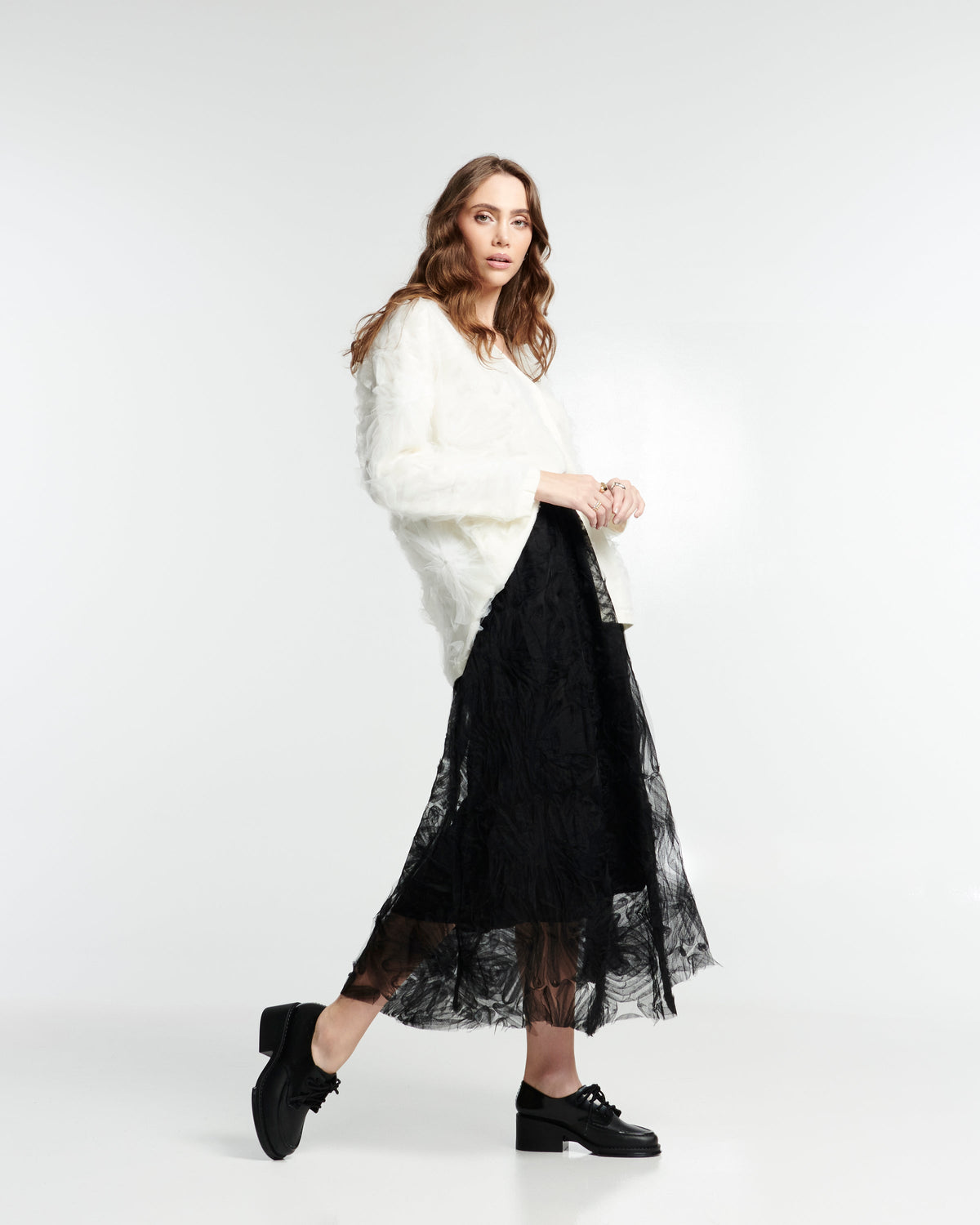Model in black lace skirt and cream sweater wearing a pair of black Tailor loafers