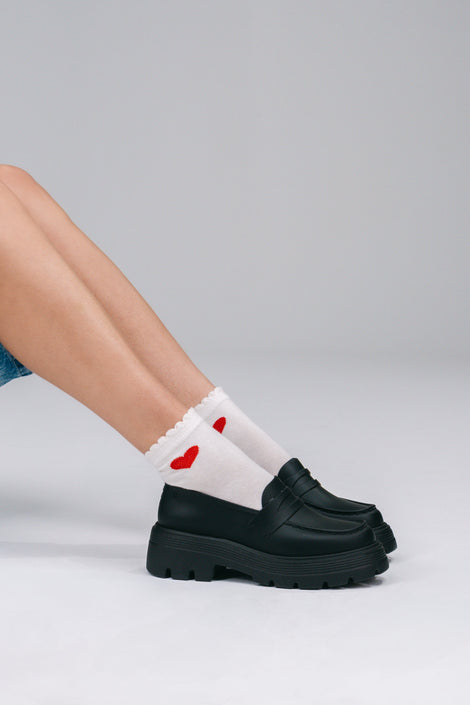 Model's legs in white sicks with red hearts wearing a pair of black Royal loafers