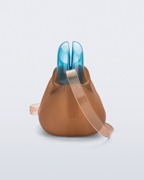 Side view of a small clear orange bag with blue clutch and long strap