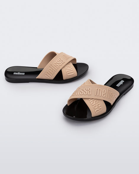 Side and angled view of a pair of beige M Lover adult slides with black sole