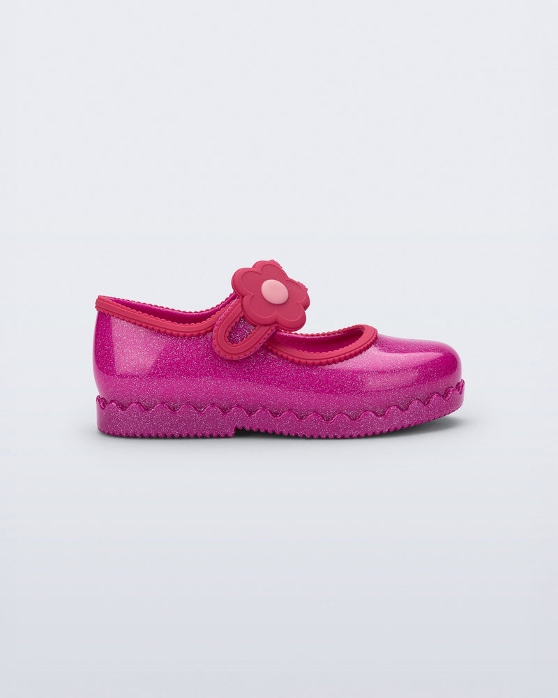 Side view of a glitter pink Hip Ballerina baby flat with flower on strap