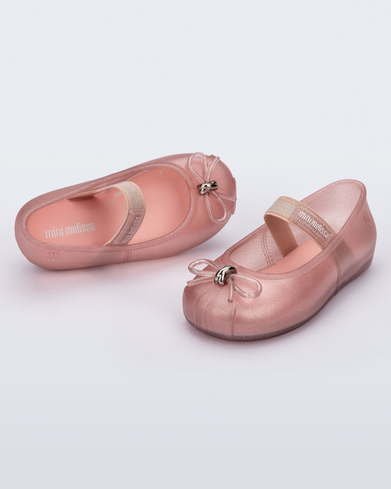 Side and angled view of a pair of pearly pink Sophie baby ballerina flats with bow