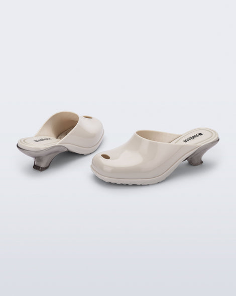 Back and angled view of a pair of light beige Gaia kitten heels with peep toe