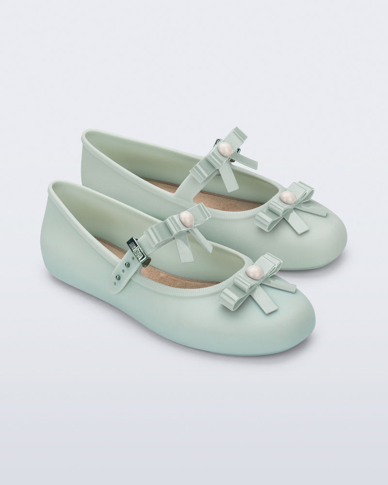 Angled view of a pair of green Soft Ballerina Bow flats with bows and a pearl in the center of each bow