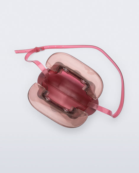 Top view of a small red bag with clear brown clutch and long strap