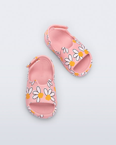 Top view of a pair of pink Free Cute baby sandals with daisy print