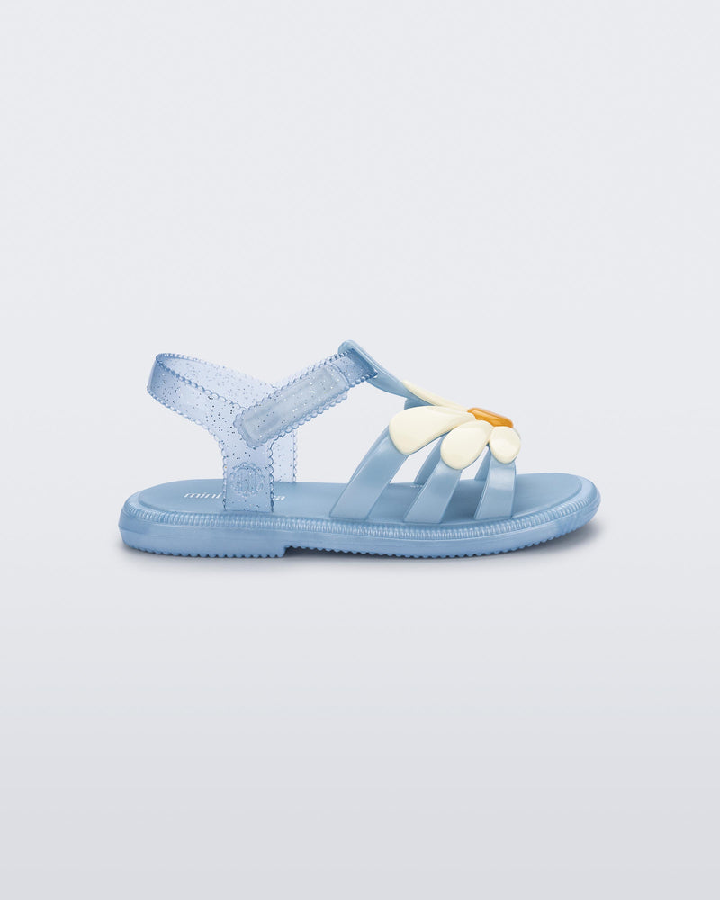 Side view of a metallic blue Hip Bloomy baby sandal with beige daisy on top