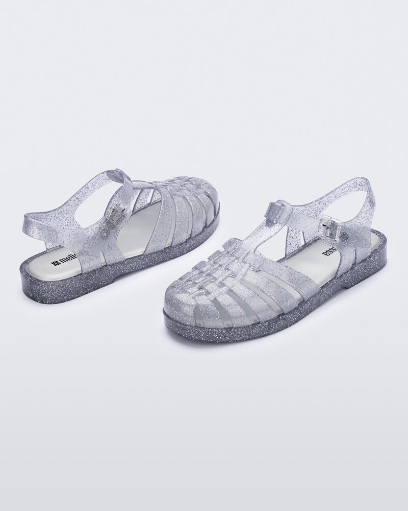 Back and angled view of a pair of glitter clear silver Possession fisherman sandals