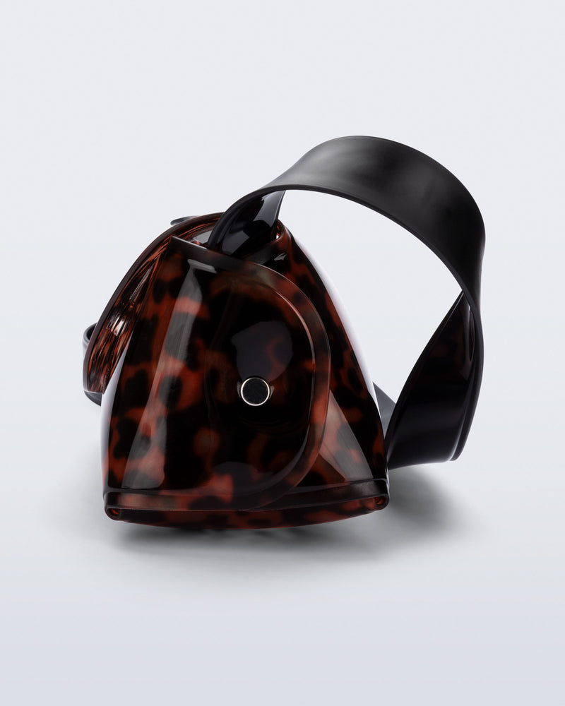Side view of a tortoise Cross Bag with adjustable black strap