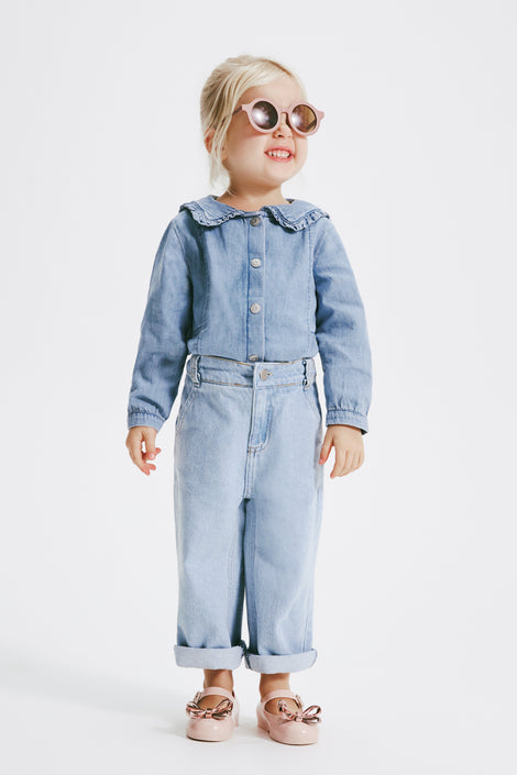 Model in jean one piece wearing a pair of sunglasses and wearing a pair of pink Sweet Love Glam baby ballerinas with bow