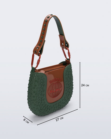 Angled view of a dark green Nina Bag + Alexandre Pavao shoulder bag with brown accents with purse dimensions of 27cm x 6cm x 24cm