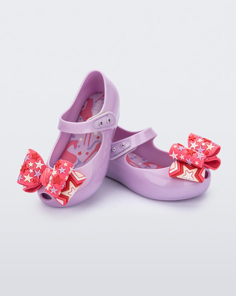 Angled view of a pair of lilac with pink star patterned bow Ultragirl Wonderland baby flats