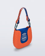 Angled view of an orange Nina Bag + Alexandre Pavao shoulder bag with blue accents