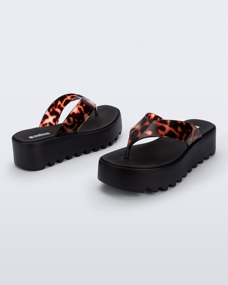Angled and back view of a pair of black Thong Platform flip flops with tortoise colored strap