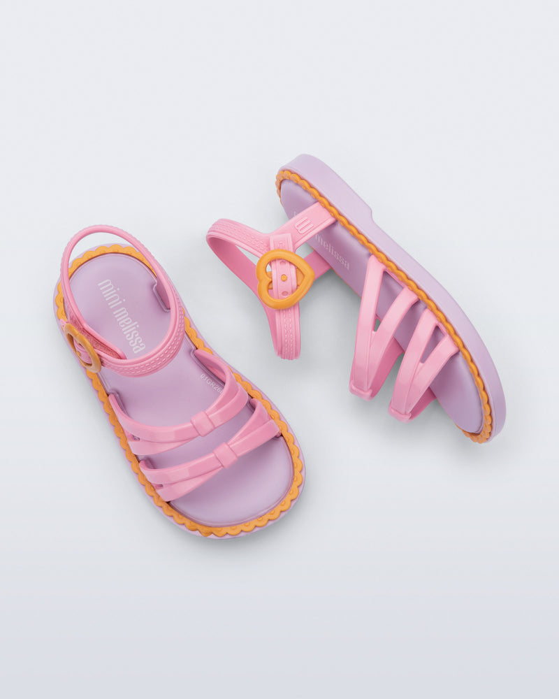 Side and Top view of a pair of pink Aurora baby sandals with purple sole and orange trim and buckle