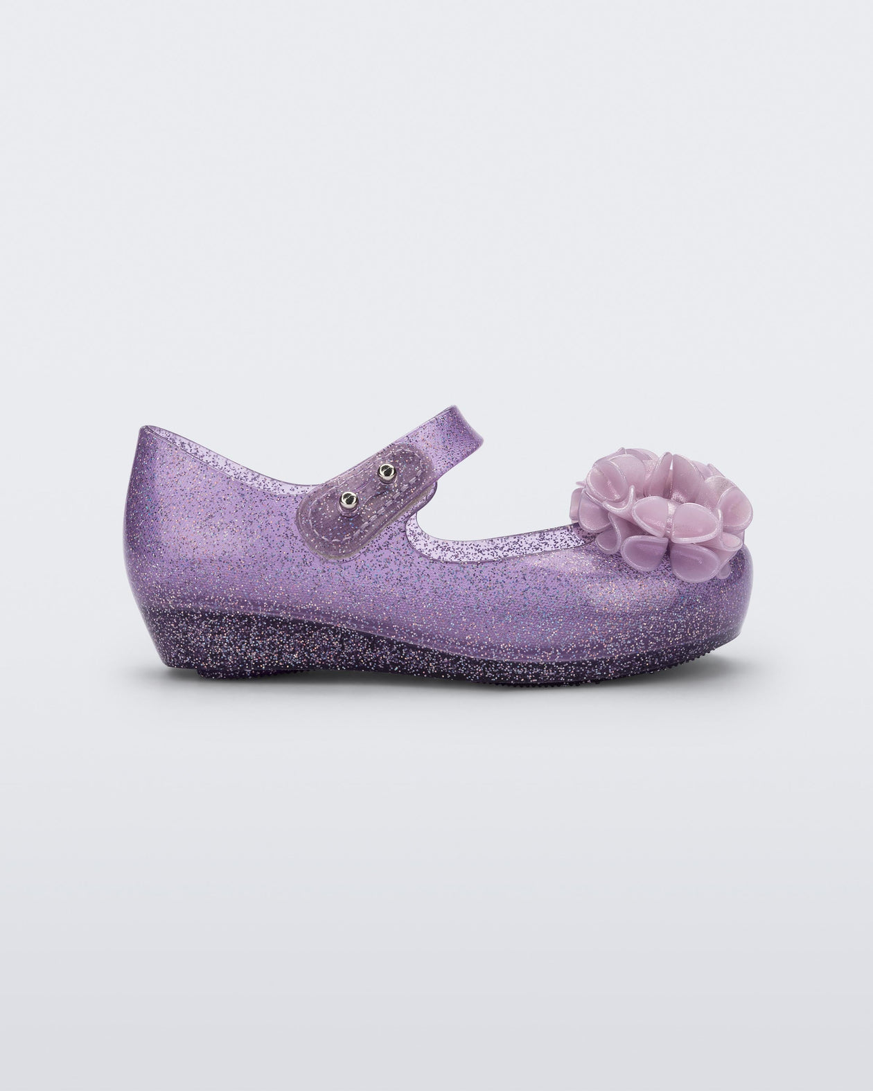Side view of a clear purple glitter Ultragirl Springtime baby flat with two purple flowers and peep toe.