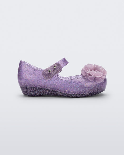 Side view of a clear purple glitter Ultragirl Springtime baby flat with two purple flowers and peep toe.