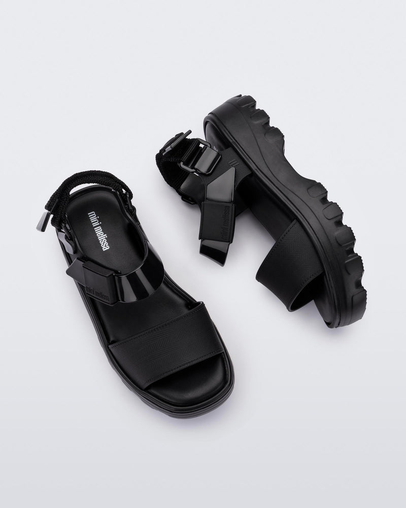 Top and side view of a pair of Mini Melissa Kick Off platform sandals in black with adjustable velcro ankle straps