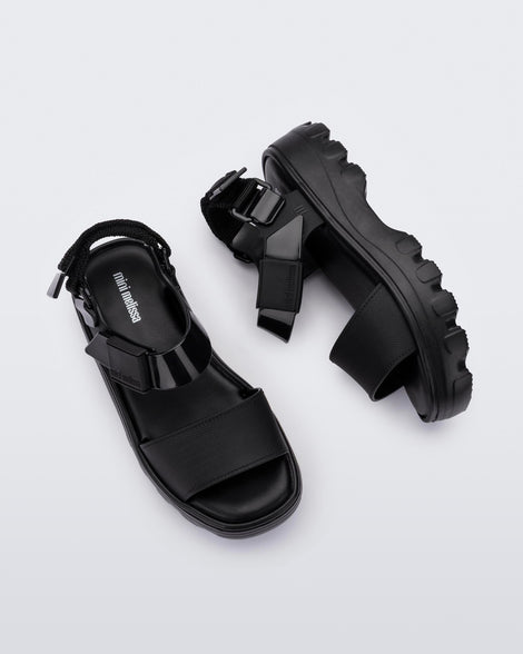 Top and side view of a pair of Mini Melissa Kick Off platform sandals in black with adjustable velcro ankle straps