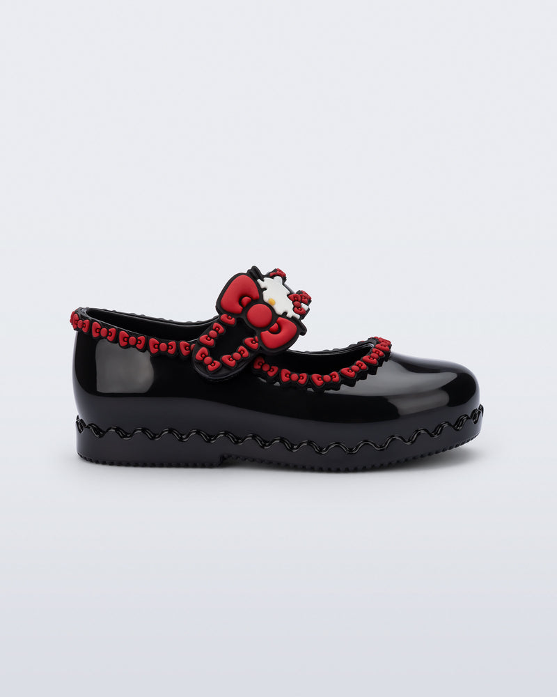 Side view of a black Hip Ballerina + Hello Kitty baby flat with red trim