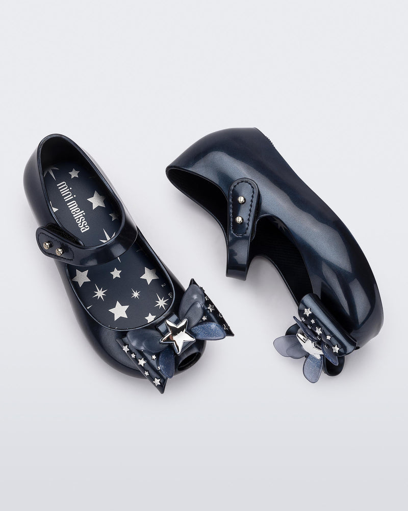 Top and side view of a pair of Mini Melissa Ultragirl peeptoe ballet flats for baby in blue with star printed butterfly bow applique.