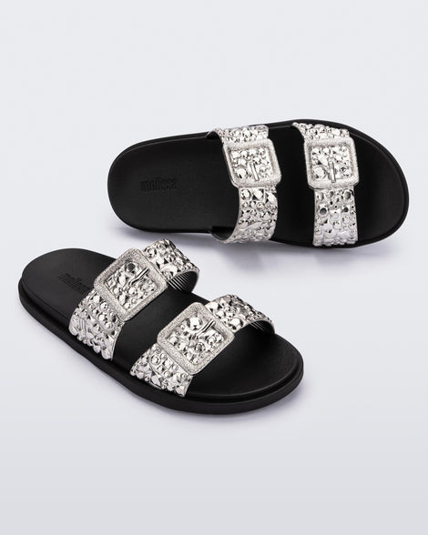Top and angled view of a pair of black Lust Slide with silver metallic buckle straps