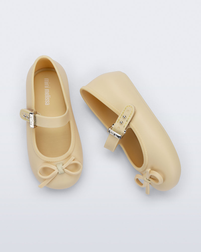 Side and top view of a pair of yellow Soft Ballerina Delicate Bow baby flats with top strap and bow