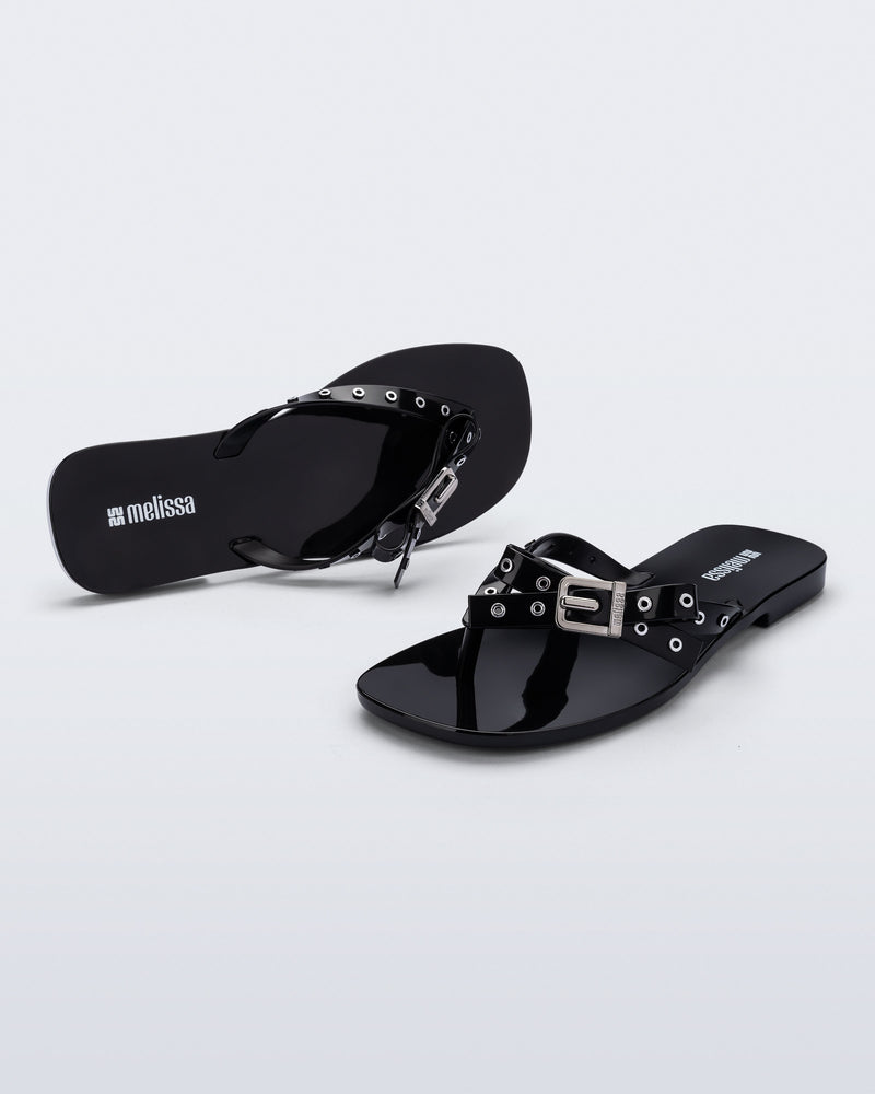 Side and angled view of a pair of black Harmonic Squared flip flops with bow on strap