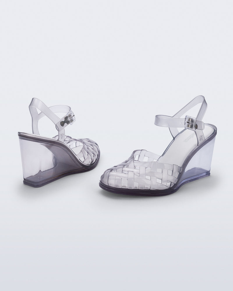Side and back angled view of a pair of clear grey Agata wedge heel sandals with ankle strap