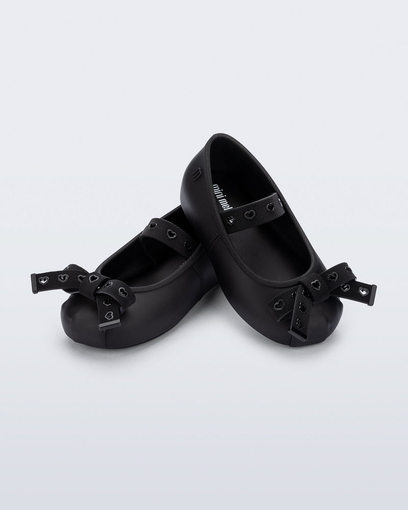 Angled view of a pair of black Sophie Crush baby ballerina flats with bow