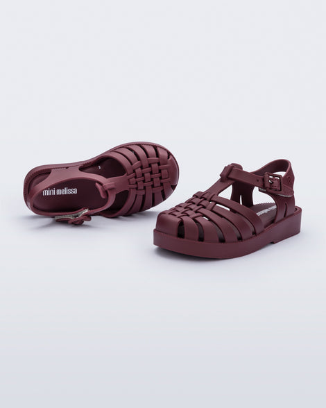 Top and side angled view of a pair of matte burgundy Possession baby fisherman sandals.