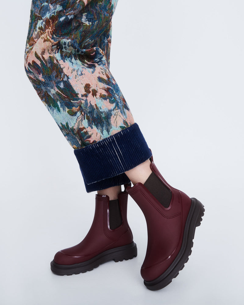 Model's legs wearing a pair of burgundy Noir boots with brown sole