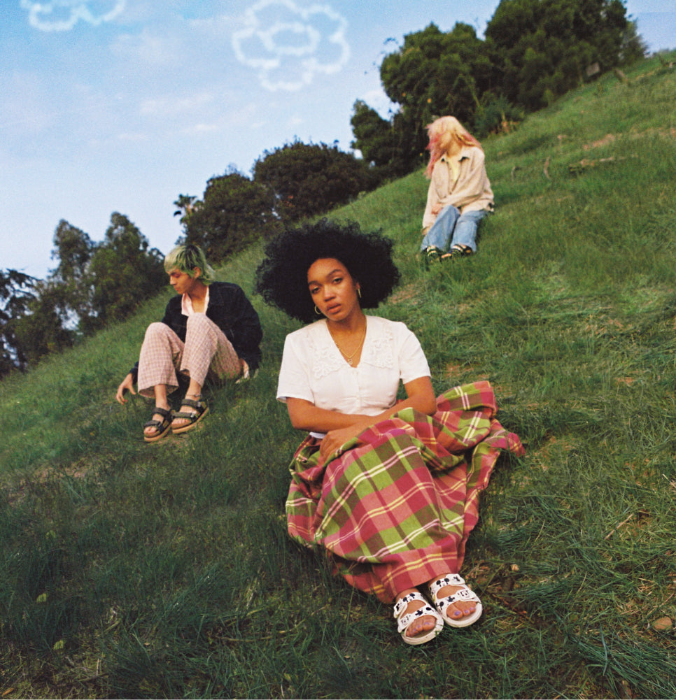 Models wearing Melissa shoes and sitting on the grass in a park