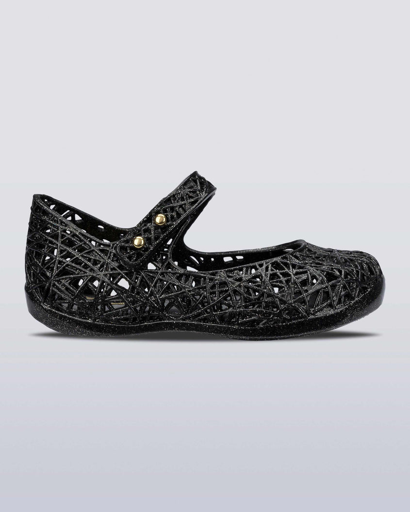 An outter side view of a Black/Silver Glitter Mini Melissa Campana Zig Zag flat with a top strap and a woven detail design.