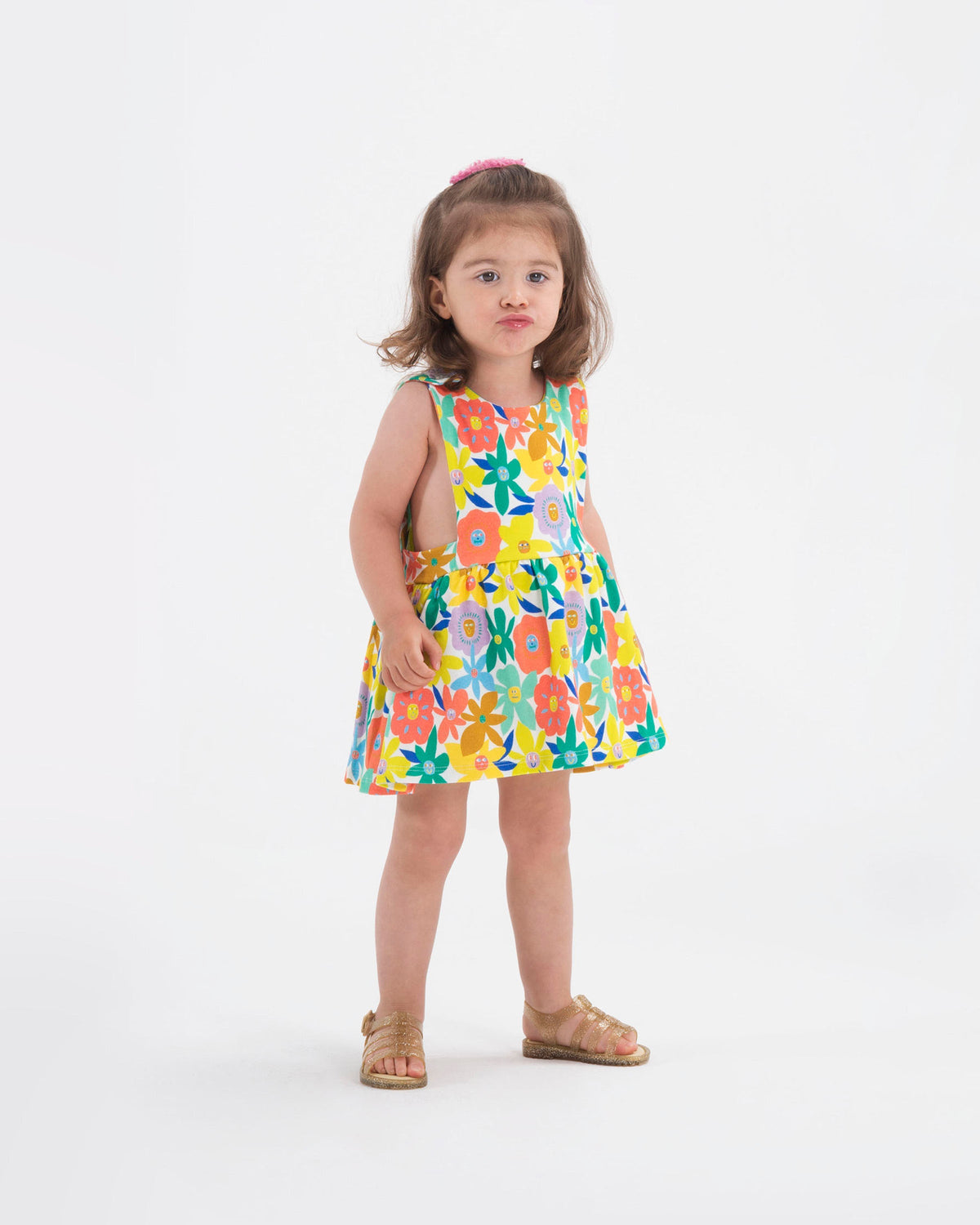 A model posing for a picture wearing a pair of clear yellow glitter Mini Melissa Flox sandals with straps.