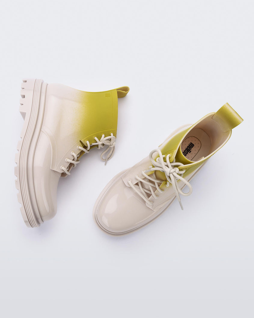 A top and side view of a pair of beige/green Melissa Coturno boots with a green into beige ombre base, beige laces and sole.