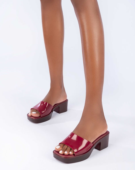 Mode'ls legs waring a pair of Melissa Shape heeled slides in Red