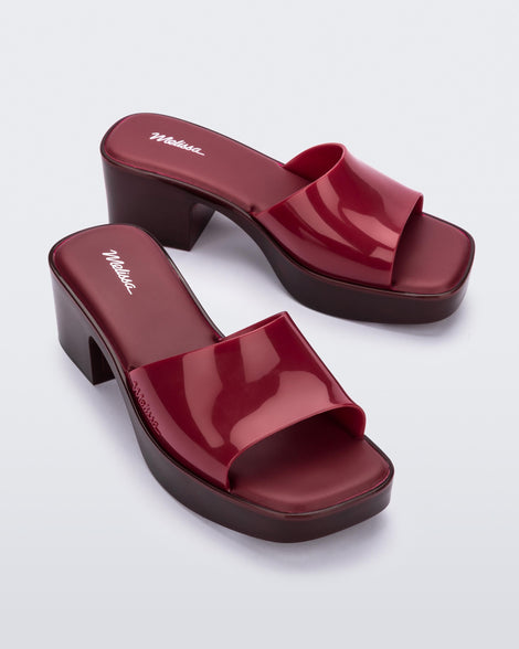Angled view of a pair of Melissa Shape heeled slides in Red